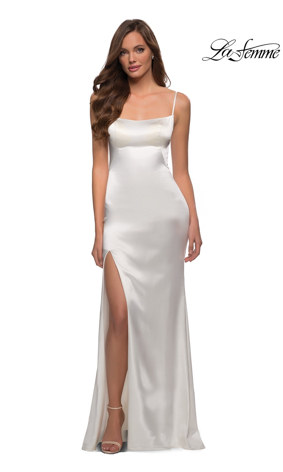 A woman in a white La Femme Open-Back Simple Long Prom Dress 29945 with spaghetti straps and a thigh-high slit stands against a plain background.
